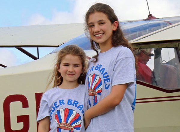 Two young girls stood next to plane at bader braves young aviator day