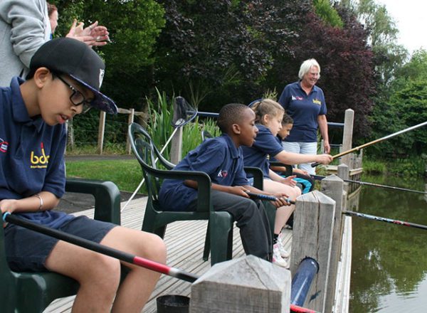 Boy holding a fish with a teacher from the British Disabled Angling Association