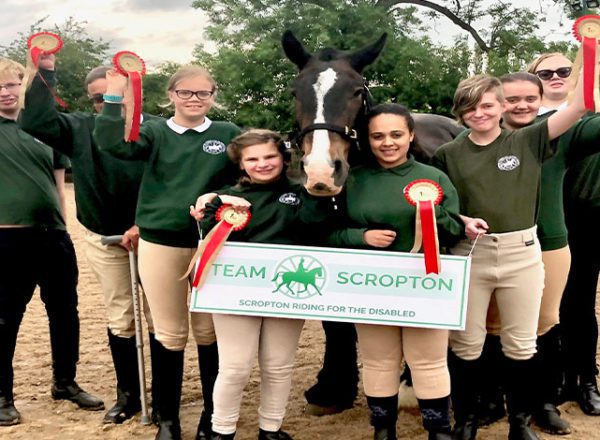 Riders at Scropton Riding for the Disabled with rosettes and a horse